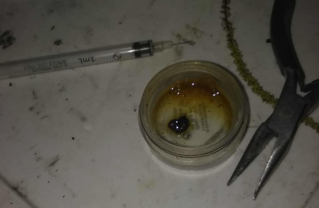 Black tar heroin, dissolving in water, and a syringe